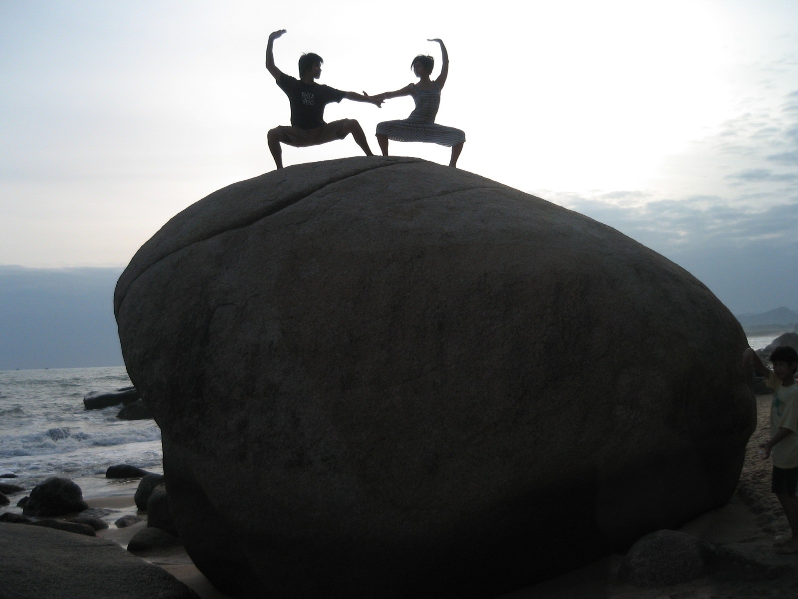 Alex and his sister practicing a martial arts pose together on a seaside rock.
