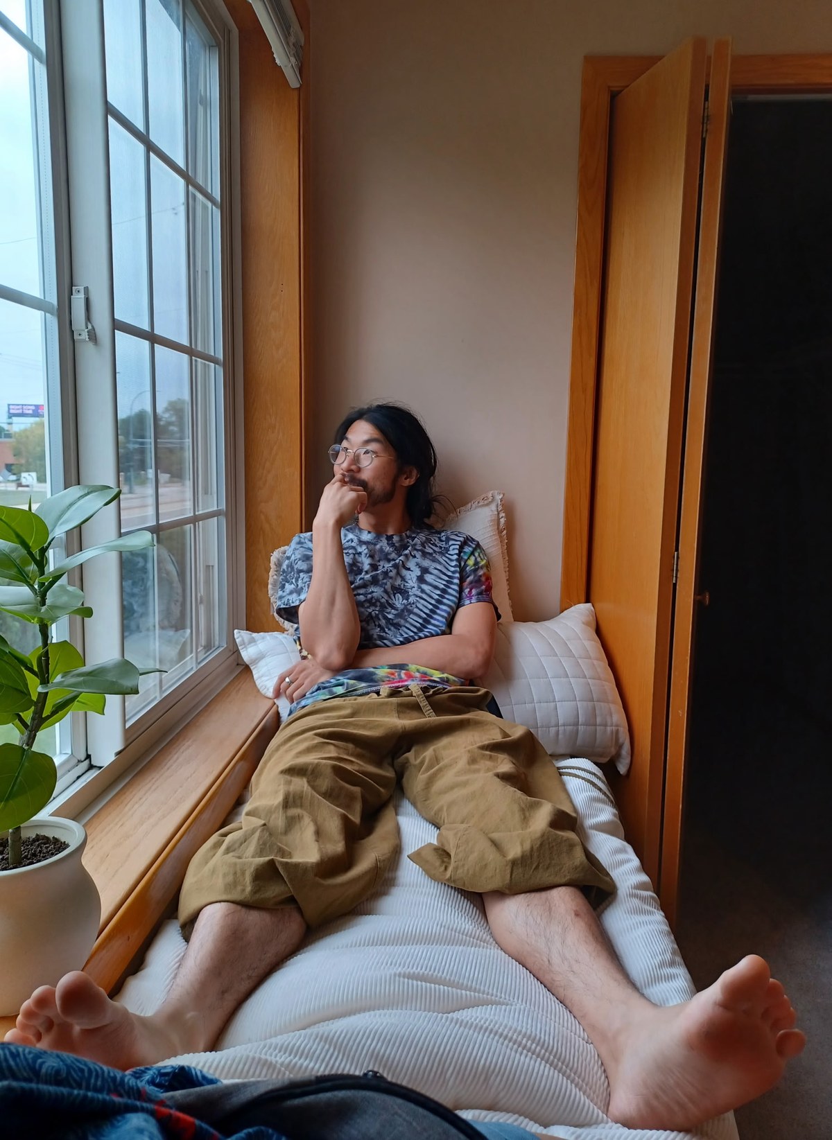 Alex sitting on the bench beside a window.